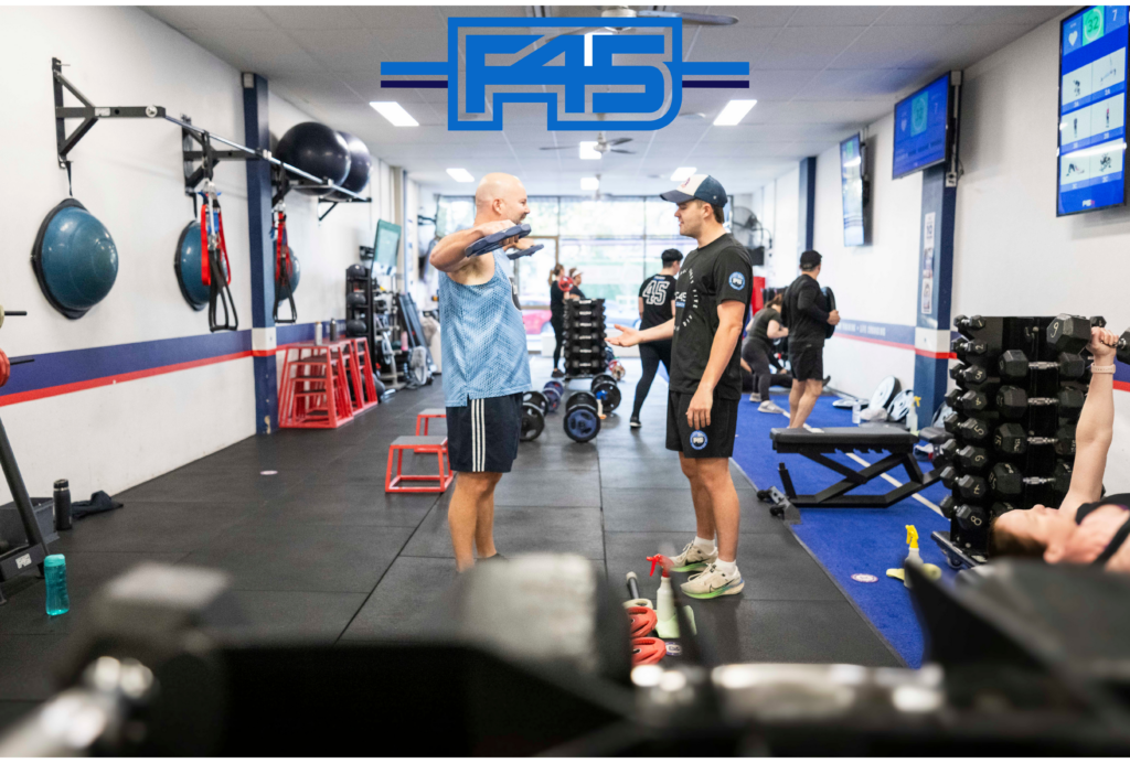 Personal trainer at F45 Thousand Oaks helping client stay motivated and accountable during a workout.